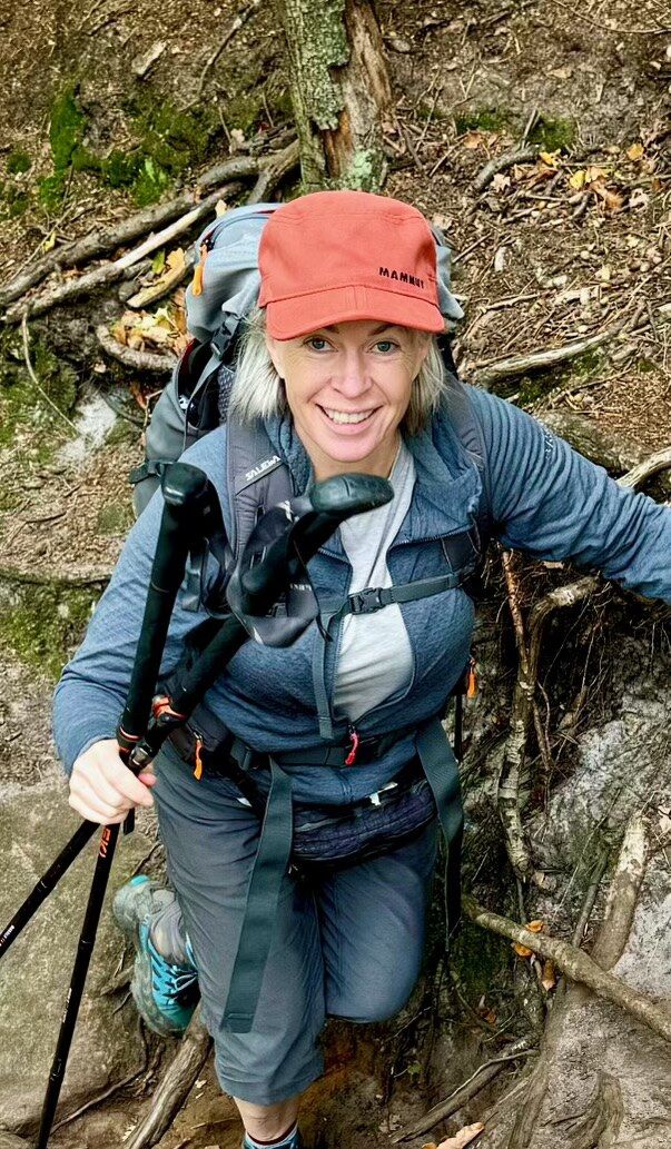Shawn Richardson on a forest trail, wearing a red cap and carrying trekking poles.
